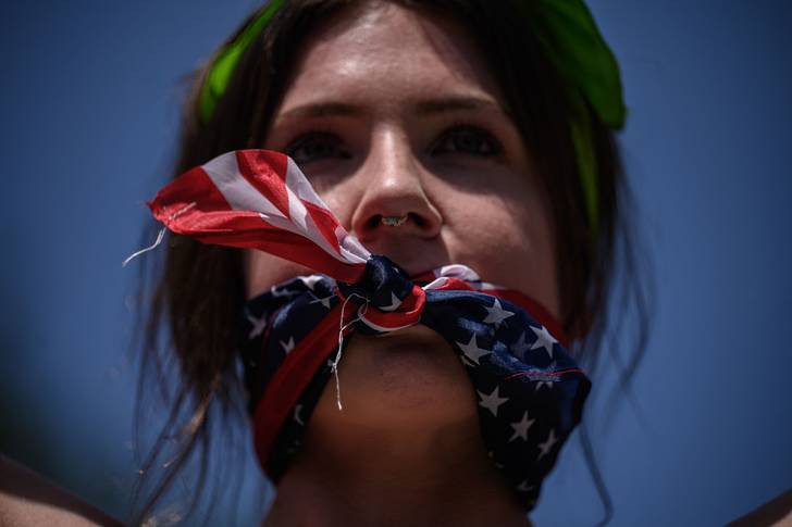 A reproductive rights activist, gagged by a scarf in the colors of the US flag, marches during a protest in New York against Supreme Court's recent ruling on abortion rights, July 4, 2022.